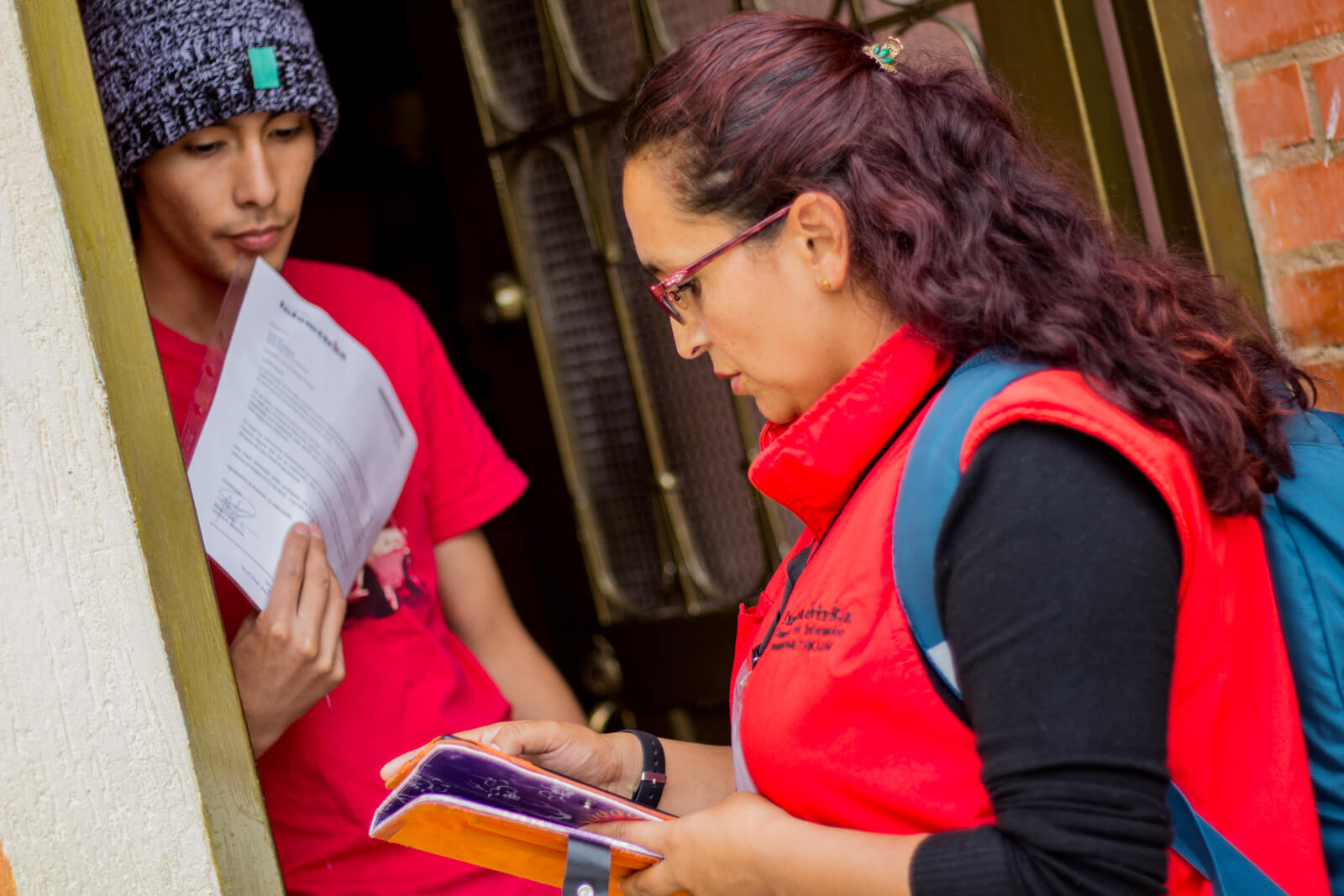 Mujer encuesadora de infoemetrika haciendo preguntas a joven con gorro