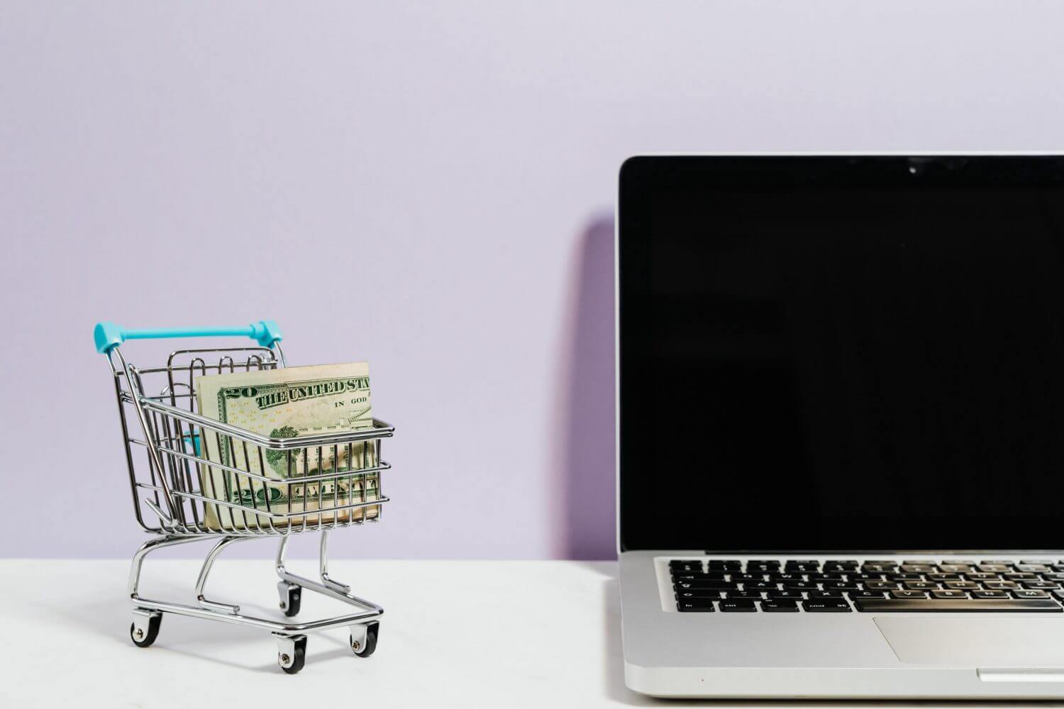 Carrito de mercado con billetes junto a un computador