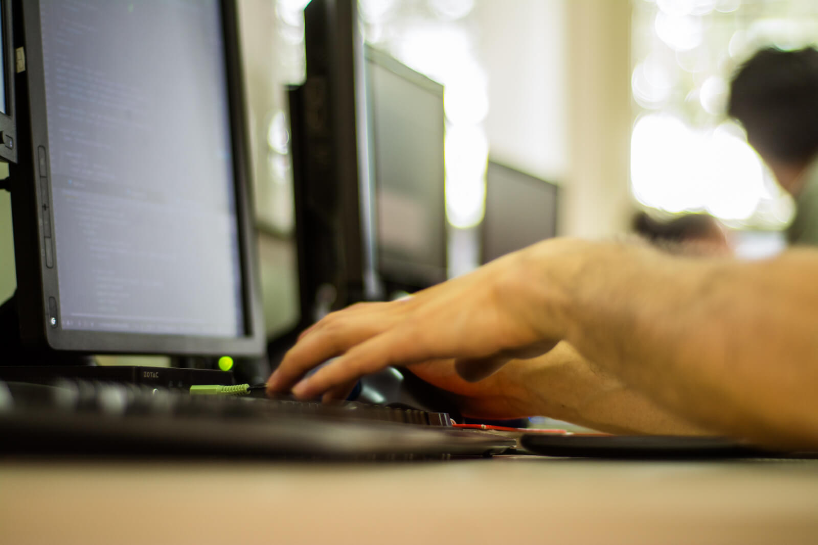 manos de hombre trabajando frente a computador en oficina
