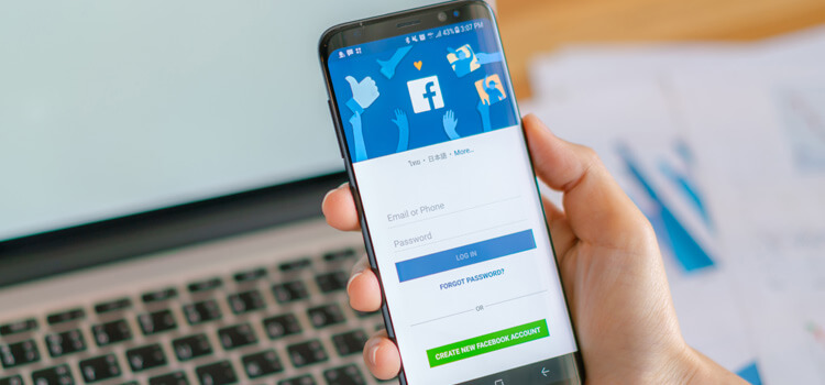 Mano sosteniendo telefono con inicio de la aplicacion facebook